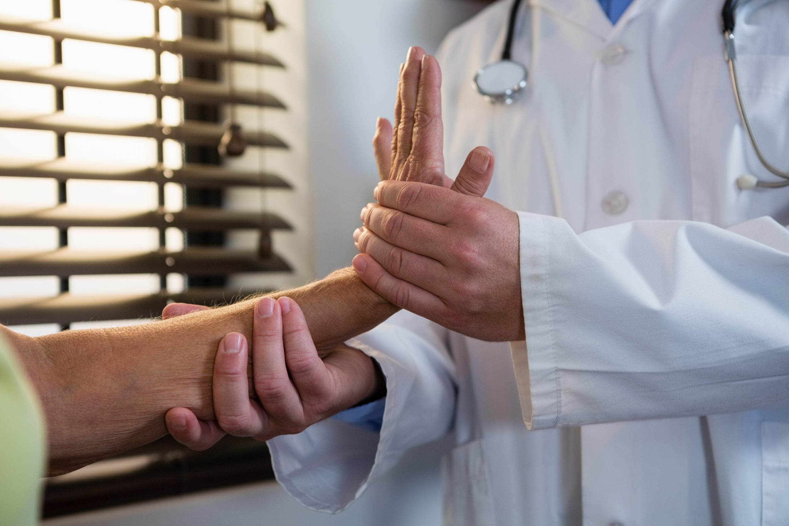 Physiotherapist examining senior patient hand in clinic